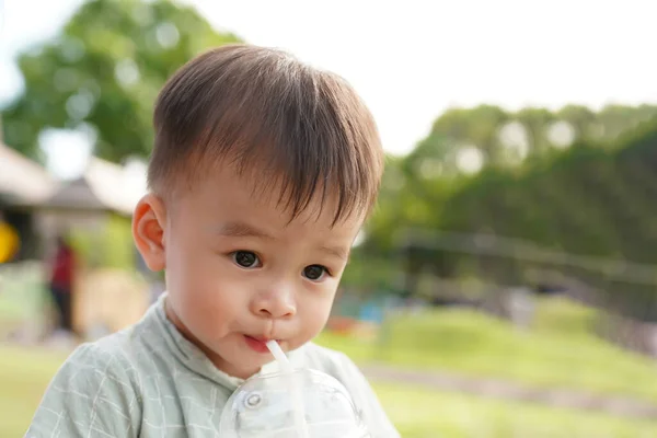 小さなアジアの少年は自分自身をリフレッシュするためにプラスチックカップで水を吸っています — ストック写真