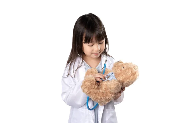 微笑的亚洲女孩扮演医生治疗毛绒玩具注射或疫苗的角色 快乐的小女孩穿着白色的医疗制服和泰迪熊病人一起玩耍 有路径的白色背景 — 图库照片
