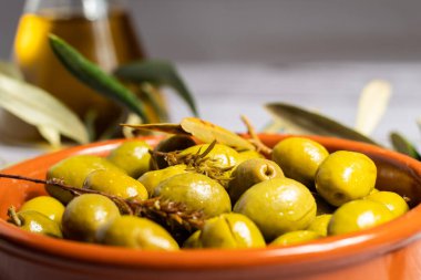 Kahverengi seramik kasede yakın plan zeytin ve bulanık arka plan.