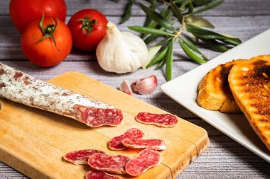 Yukarıdan çekilen bir kırbaç kapağı, ahşap bir masa ve gri arka planda domates ve sarımsak süslemesi ile.