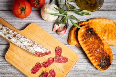 Yukarıdan çekilen bir kırbaç kapağı, ahşap bir masada domates ve sarımsak süslemesi ile.