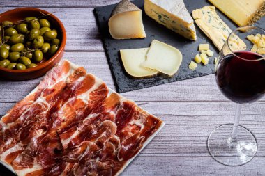 Gri bir kırsal masada serrano jambonu ve peynir.