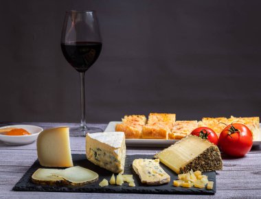 Yanında bir bardak kırmızı şarap ve domatesli peynir masası.