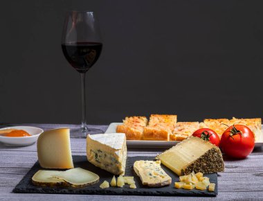 Yanında bir bardak kırmızı şarap ve domatesli peynir masası.