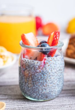 Ön planda çilek ve yabanmersinli bir bardak chia.