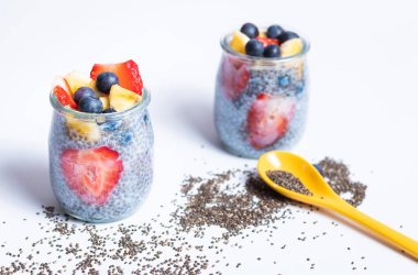 Sarı kaşık ve chia tohumlarıyla izole edilmiş iki bardak chia.