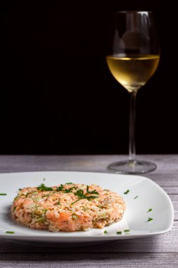 Avokado somonu tartar ve açık gri arka planda bir bardak beyaz şarap.