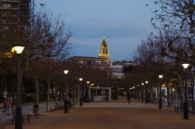 Palamos, Girona, İspanya, Desembre, 30, 2020. Palamların fotoğrafı. Balıkçılar Heykeli 'nden çekilmiş, böylece güzel ışıklandırılmış çan kulesini ve tipik kumlu güvertesini görebilirsiniz.