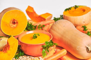 Balkabağının faydaları. Kabaklarla dolu bir kırsal masada kabaklar, küçük bir portakal kabuğunda püre ve beyaz arka planda dekoratif tohumları olan balkabağı parçaları.