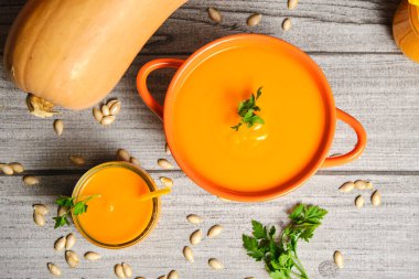 Yukarıdan çekilmiş dekoratif bir balkabağı smoothie ile balkabağı püresi, gri bir kırsal masa üzerinde, boruları ve bitkileriyle tamamlamak için