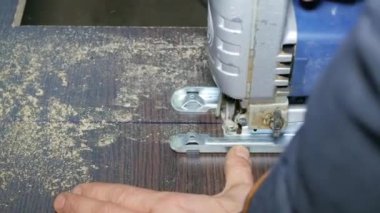 Erkek bir inşaatçının yakın çekimi elektrikli bir yapbozla ahşabı keser..