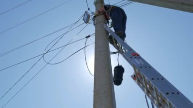 Elektrik işi, elektrik direğini tamir eden adam tüm güvenlik ekipmanlarını giyiyor.