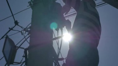 Günbatımının arka planında yüksek voltajlı elektrik direği olan elektrik mühendisi..
