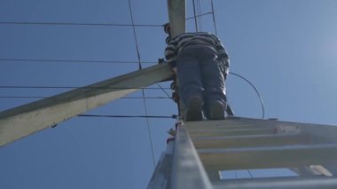Elektrikli siluet mühendisi merdivenlerde duran elektrik direği üzerinde çalışıyor.