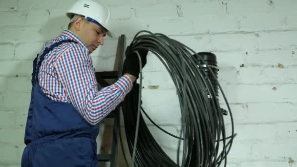 Komunikační technik točí optický kabel z velkého dřevěného bubnu kabelu. — Stock video
