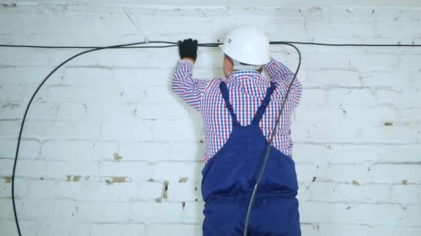 Een communicatie ingenieur draait een optische kabel van een grote houten kabeltrommel. — Stockvideo