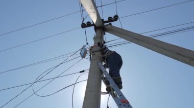 Elektrikli siluet mühendisi merdivenlerde duran elektrik direği üzerinde çalışıyor.