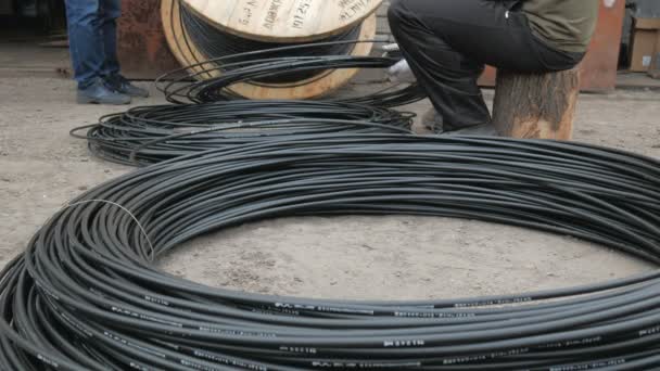 Inżynier komunikacji obraca kabel optyczny z dużego drewnianego bębna kablowego. — Wideo stockowe