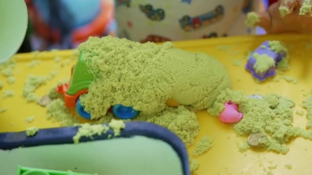 Крупним планом маленький хлопчик грає з пластиковими іграшками і кінетичним піском — стокове відео