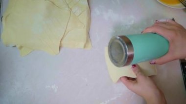 Hamur un serpiştirilmiş, merdaneyle yuvarlanmış, yumuşak odaklı, hafif ışıklı, ağır çekimde.