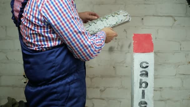 Μηχανικός λειτουργεί δίπλα bollard σήμα κατά λευκό τοίχο με οπτική ίνα συνδετήρα — Αρχείο Βίντεο