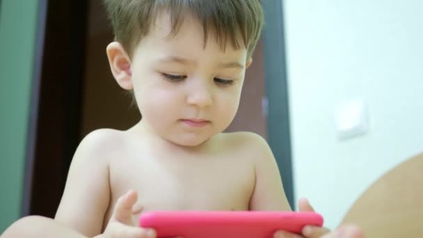 Милий маленький хлопчик дивиться мультфільми по телефону — стокове відео