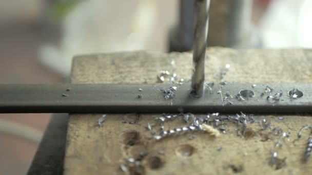 Een man is gespecialiseerd in het boren van gaten in een boormachine in een metalen werkstuk. — Stockvideo