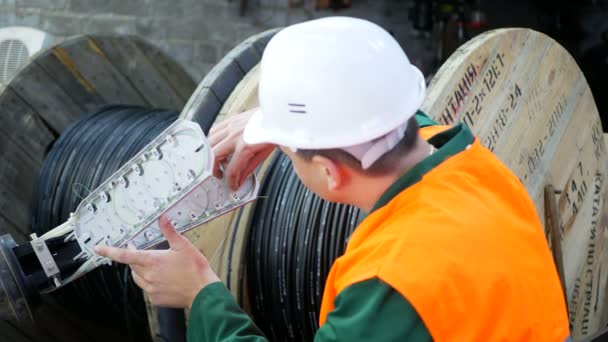 Un ingeniero de comunicaciones trabaja con un cable de fibra óptica. — Vídeo de stock