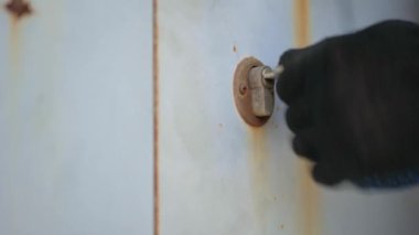 Siyah eldivenli bir el anahtarı anahtar deliğinde elle çevirir.