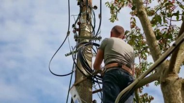 Elektrik işi, elektrik direğini tamir eden adam tüm güvenlik ekipmanlarını giyiyor.