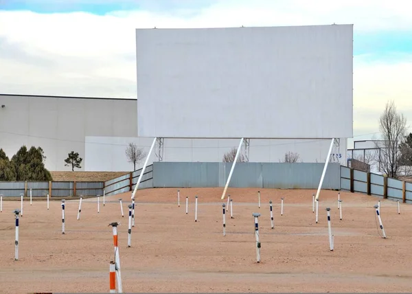 A drive-in theater or drive-in cinema is a form of cinema structure consisting of a large outdoor movie screen, a projection booth, a concession stand, and a large parking area for automobiles.