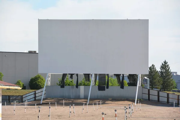 A drive-in theater or drive-in cinema is a form of cinema structure consisting of a large outdoor movie screen, a projection booth, a concession stand, and a large parking area for automobiles.