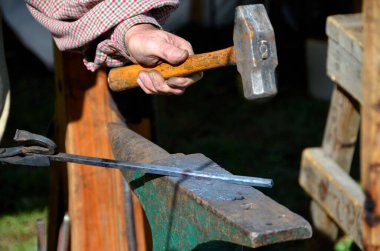 Demirci alet yapmak için demire vuruyor.