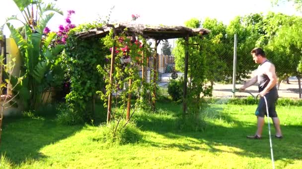 Человек поливая сад из шланга (4K ) — стоковое видео