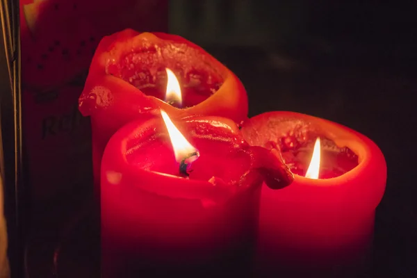 Tři červené svíčky hoří ve tmě — Stock fotografie