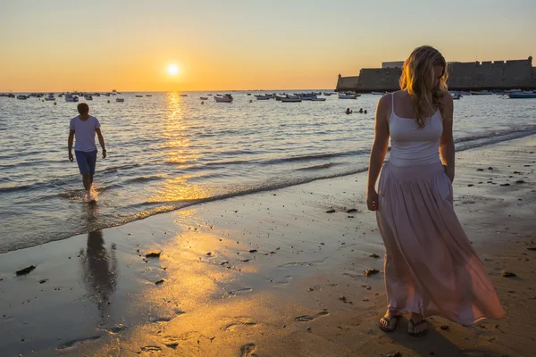 Paar wandelingen op het strand bij zonsondergang — Stockfoto