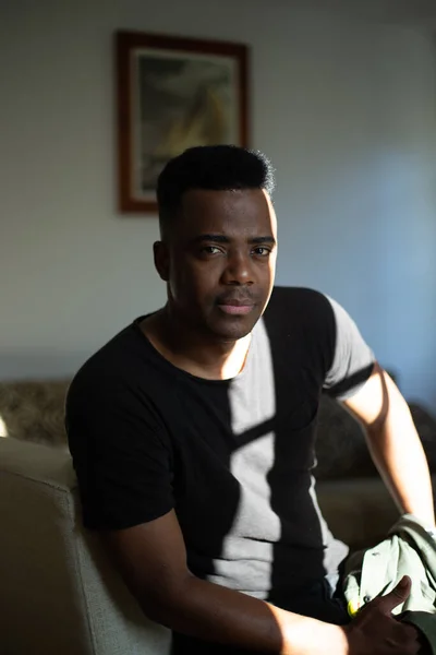 Vücudundaki ve gömleğindeki gölgeler şekillenirken Afrikalı Amerikalı doğrudan kameraya bakıyor.