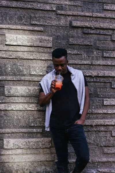 Siyah tişört ve kotla portakal suyu içen Afro-Amerikalı.