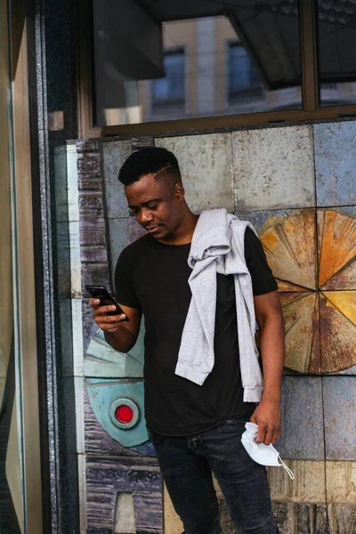 Afro-Amerikan güzel bir arka planda telefona bakıyor.