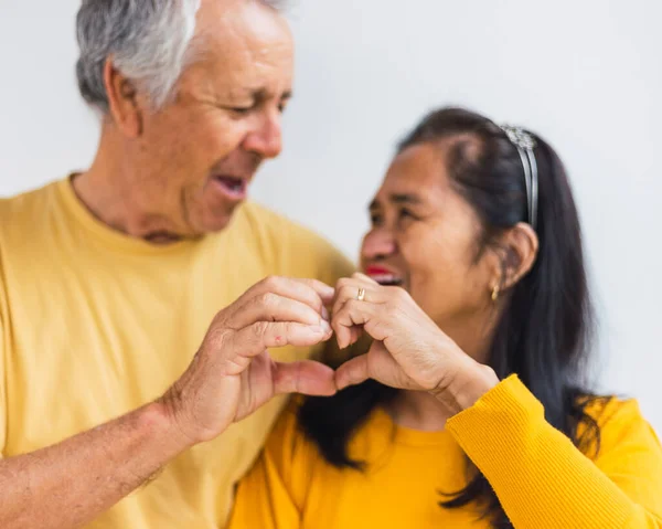 Mutlu yaşlı çift elleriyle kalp yapıyor.