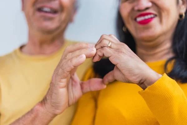 Tanımlanamayan yaşlı çift elleriyle kalp yapıyor.