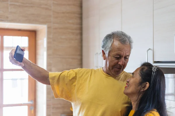 Orta yaşlı bir evlilik, birbirine bakarak selfie çekiyor.