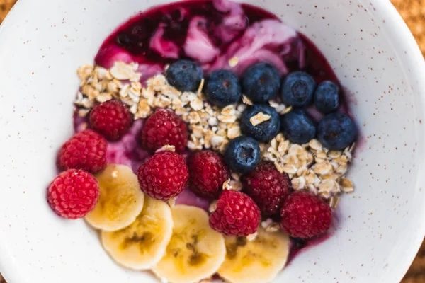 Yulaf, ahududu, yoğurt ve muzlu sağlıklı meyve kasesi.