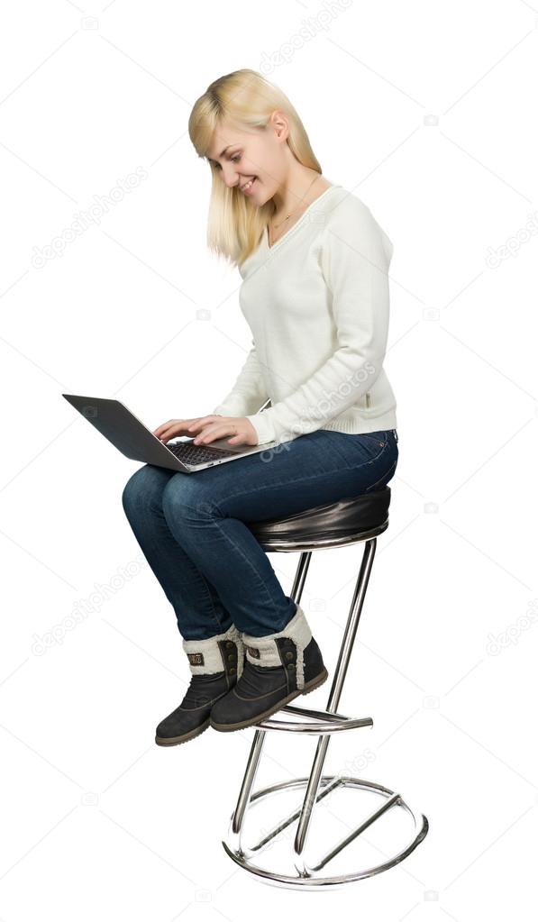 Business woman sitting a high chair and works on the laptop