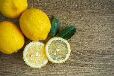 Limon dilimleri birkaç limonu yan yapraklarla bir araya getirir. Ahşap zeminde Yukarıdan bakınca, boşluk boş..