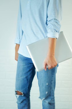 Bir dizüstü bilgisayar ve cep telefonu tutarak yürü, uyluk seviyesinde, vücudun alt kısmında, dikey olarak..