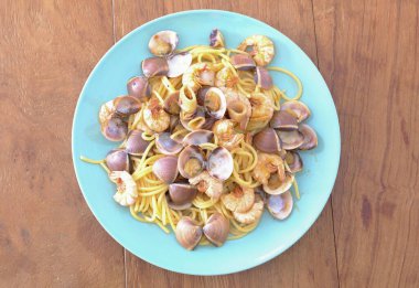 Lezzetli taze ev yapımı kalamar ve karidesli deniz ürünleri spagettisi ahşap masanın üstünde servis ediliyor, İtalya.