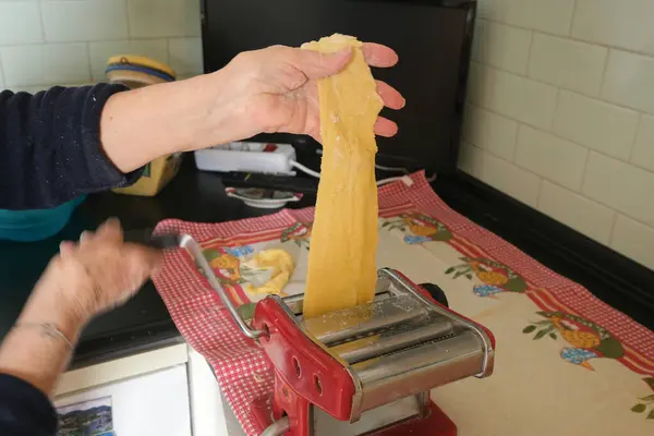 Older woman making pasta with roller, Italy