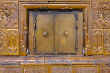 Eski bir evin odasındaki seramik bir sobanın yüzeyinde antika teçhizatlı fırın kapıları..