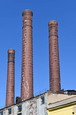 Büyük şehirlerin ekolojisi. Bir insan için ilerleme. Eski bir şehrin elektrik santralinin tuğlalarından yapılmış duman boruları mavi gökyüzü arka planına karşı. 